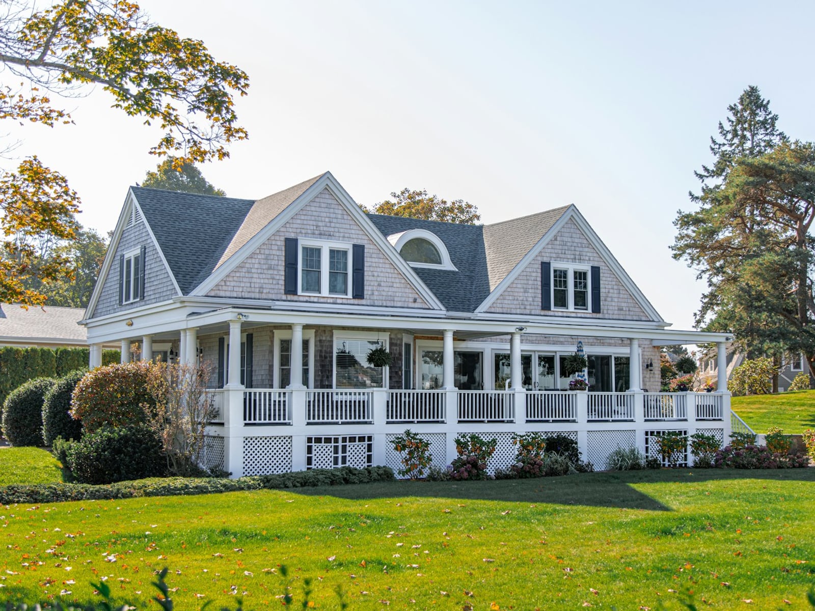 Well-kept New England–style home with wraparound porch and shingle siding.